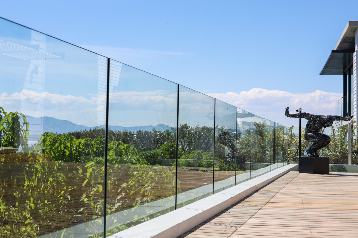 Frameless glass balustrade along a rooftop patio deck with garden and mountain views