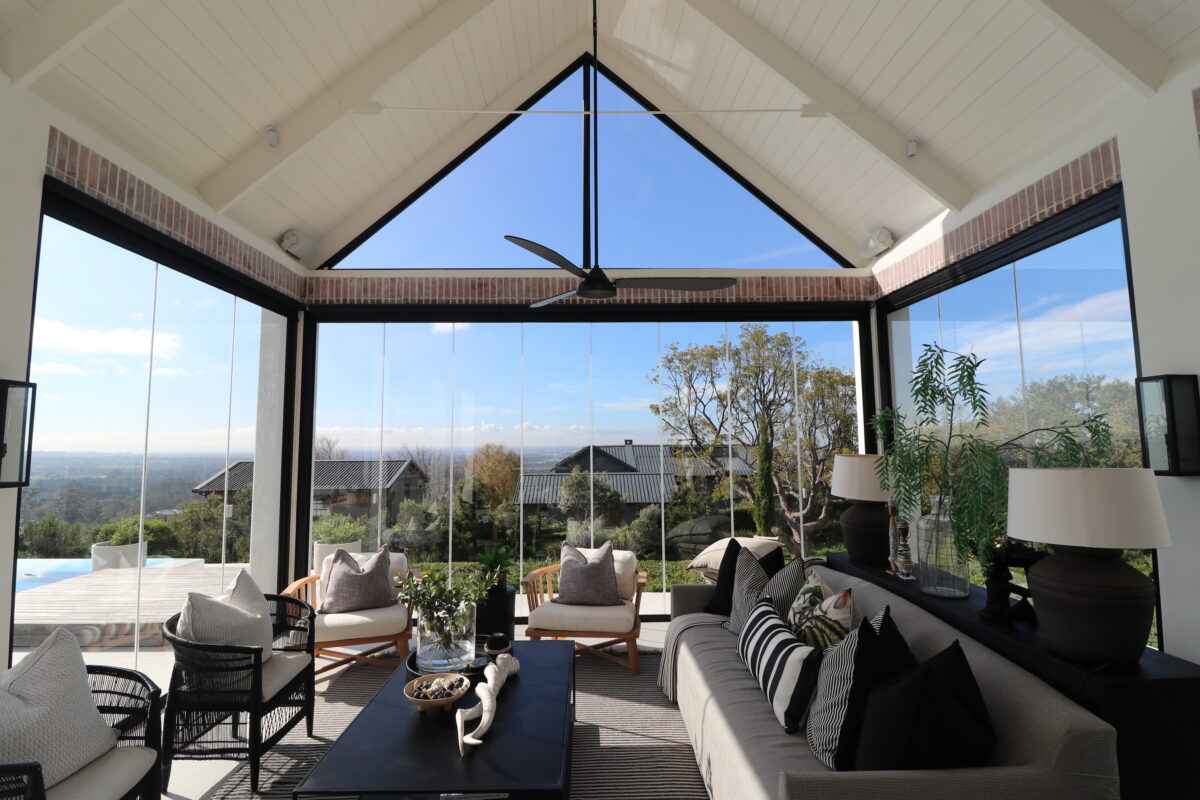 Frameless glass doors wrapping a pitched-roof living space with valley views